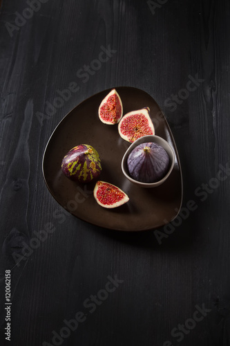 Juicy ripe figs on a plate. Dark wooden background. Top view