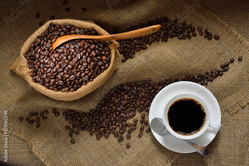 Top view of cup of coffee and coffee beans on burlap background