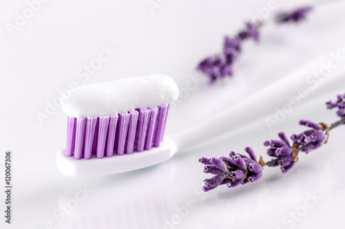 sqweezed toothpaste and toothbrush with lavander on white background