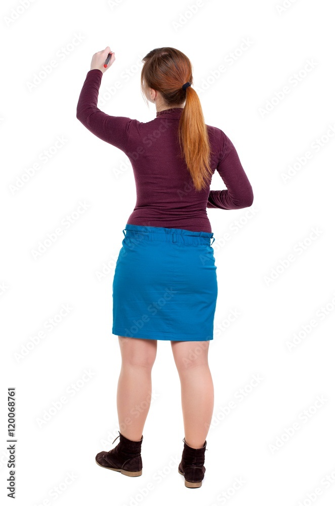 back view of writing beautiful woman. Girl with red hair tied in a pigtail draws felt-tip pen on the wall. back view of writing beautiful woman. Girl with red hair tied in a pigtail draws felt-tip pen on the wall.