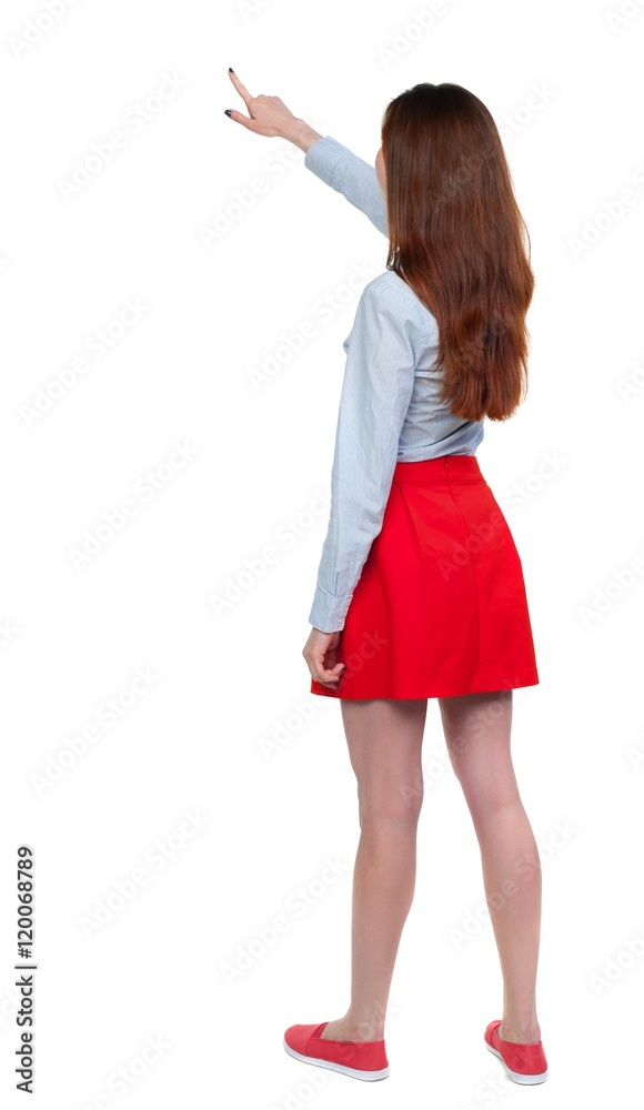 Back view of pointing woman. beautiful girl. Long-haired brunette in red skirt showing thumb up.