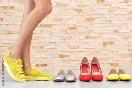 Woman choosing shoes on brick wall background