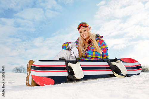 Young female snowboarder sitting on slope