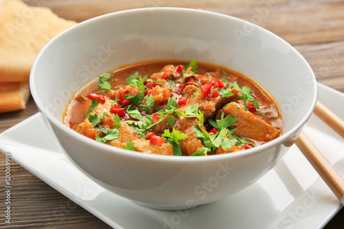 Tasty chicken curry in soup plate and chopsticks on table