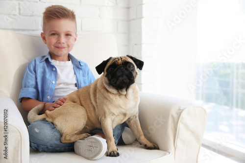 Cute boy with pug dog on couch