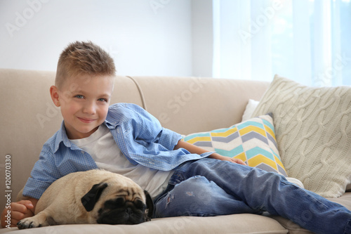 Cute boy with pug dog on couch