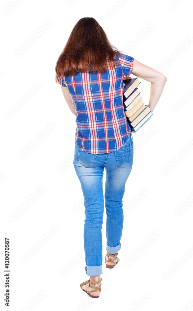 Girl comes with stack of books. back side view. Girl in plaid shirt holding out arm textbooks. Girl comes with stack of books. back side view. Girl in plaid shirt holding out arm textbooks.