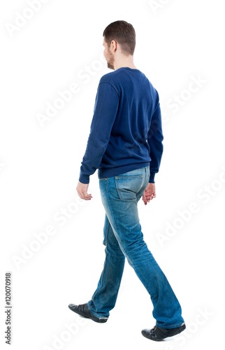 Back view of going handsome man. walking young guy . bearded man in blue pullover goes diagonally.