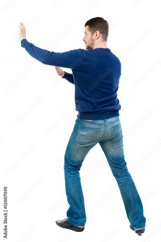 back view of business man pushes wall. bearded man in blue pullover shoves something on the side. back view of business man pushes wall. bearded man in blue pullover shoves something on the side.