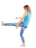 back view of woman funny fights waving his arms and legs. Isolated over white background. The blonde in a blue shirt and jeans, raised her leg.