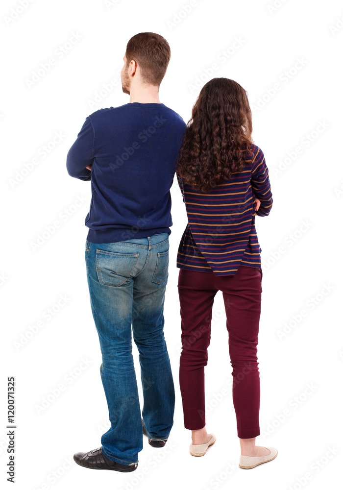 Back view of young embracing couple (man and woman) hug and look into the distance. Swarthy girl and a bearded man standing back to back. Back view of young embracing couple (man and woman) hug and look into the distance. Swarthy girl and a bearded man standing back to back.