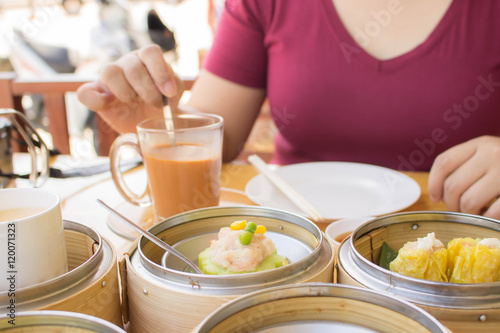 young woman eating dimsum and thai tea blur background