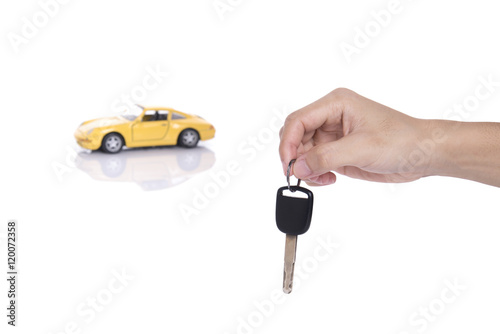 hand holding car key and yellow miniature car isolated on white background