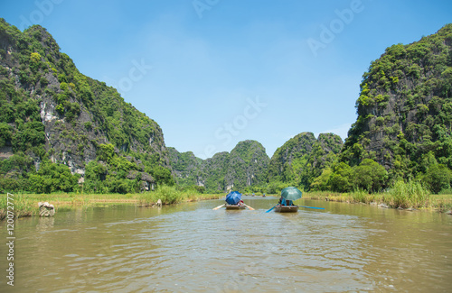 Tourists asia traveling in boat along nature the river and mountain. at Tam Coc portion, Ninh Binh Province, Vietnam. Rower using her feet to propel oars. landscape river and mountain