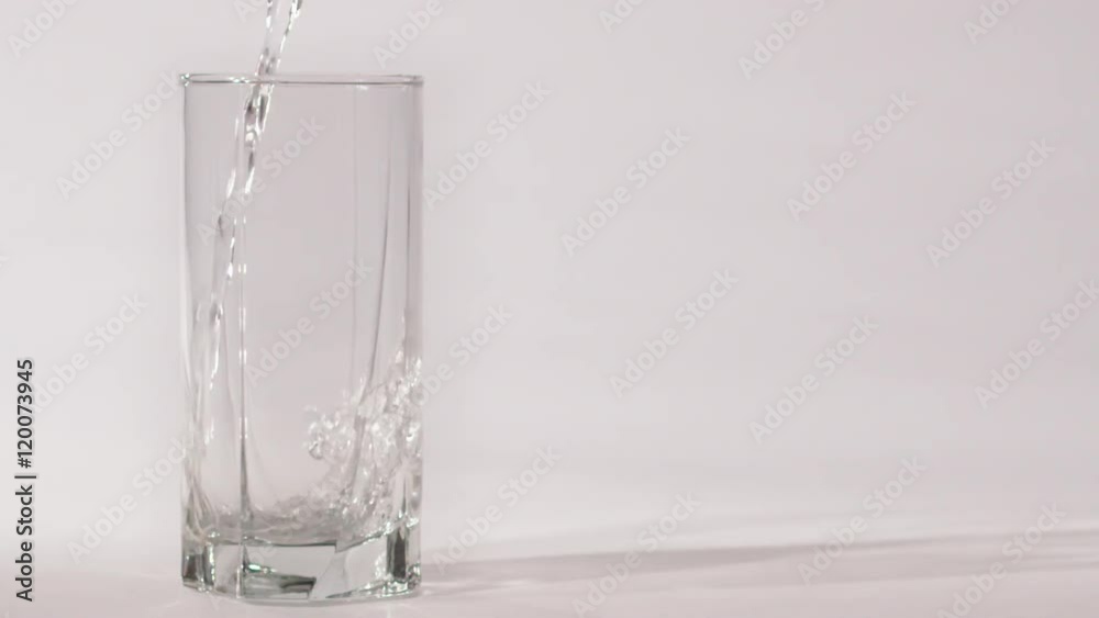 water is poured in a glass, close-up on white background slow motion water is poured in a glass, close-up on white background slow motion