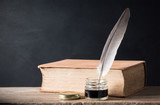 still life photography : inkwell and quill with old books on art dark background