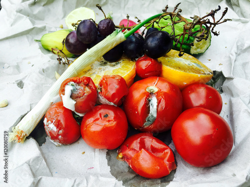 Verschimmelte Tomaten und Obst auf grauem Papier
