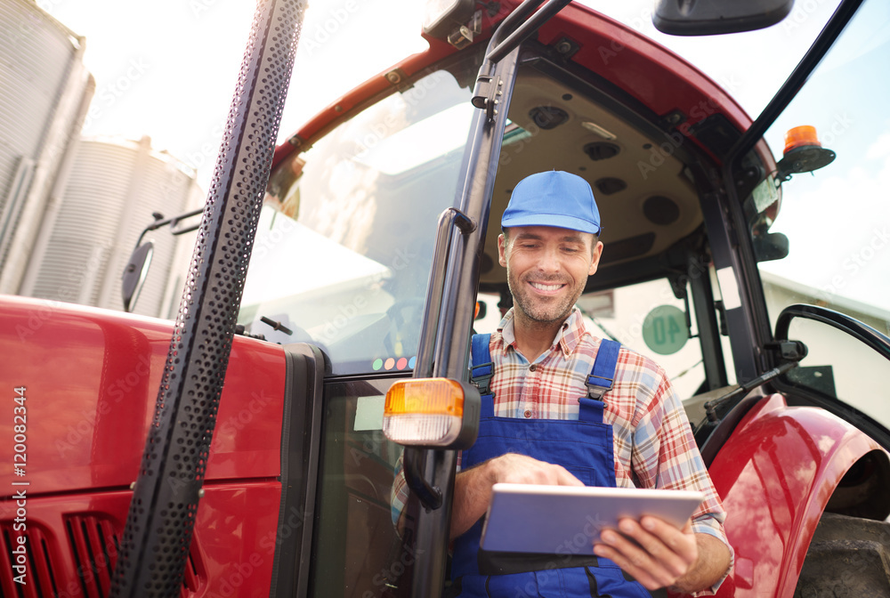 Obraz premium Farmer with digital tablet in his tractor