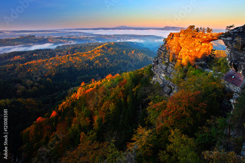 Pravcicka brana rock bridge monument in autumn colours. Czech national park Ceske Svycarsko, Bohemian Switzerland park, Czech Republic. Autumn landscape with fog. orange trees in autumn landscape.