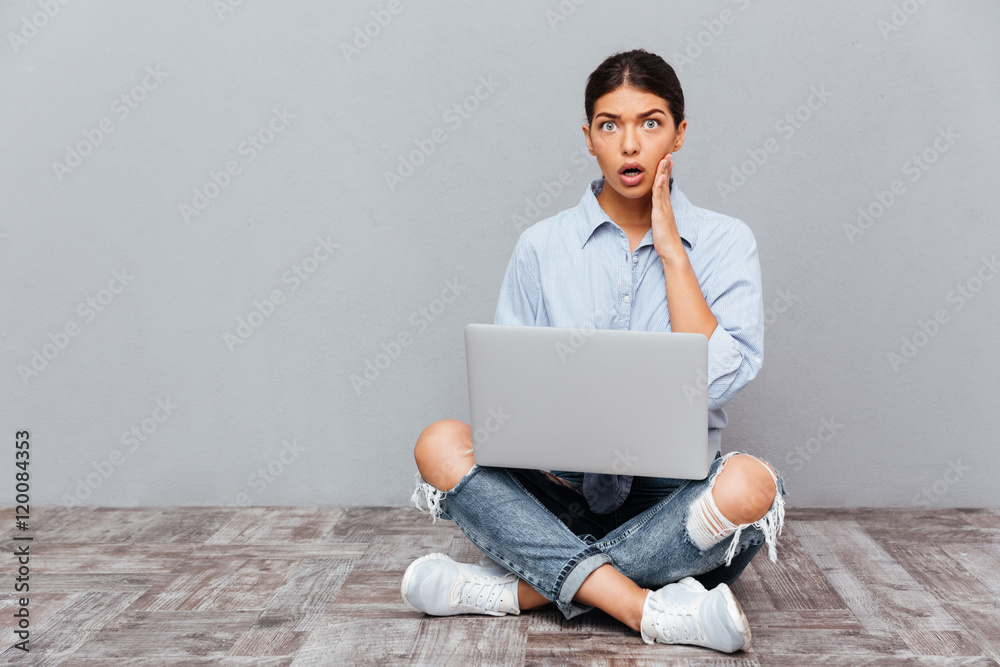 Portrait of shocked woman sitting on the floor with laptop Portrait of shocked woman sitting on the floor with laptop