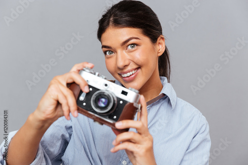 Portrait of a smiling young brunette girl holding photo camera