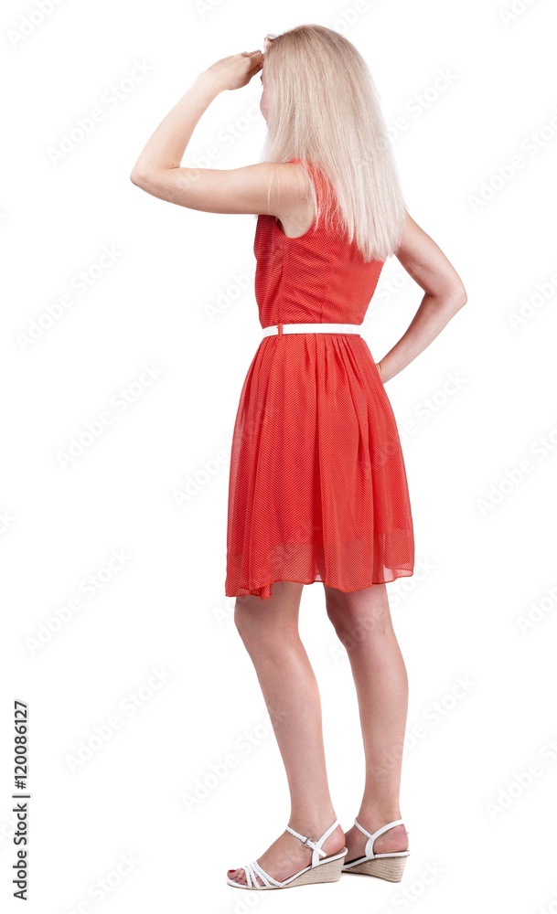 back view of standing young beautiful  blonde woman. she shyly looks at something. girl  watching. Rear view people collection.  backside view of person.  Isolated over white background.