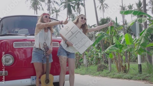 Hippie Girls with a White Panel in Hands Catch Passing Car near the Broken Minivan. Slow Motion photo