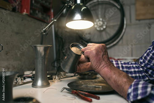 Fotografija Hands of senior man inspecting antique tin vase