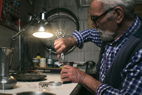 Man fixing antique vase with pincers