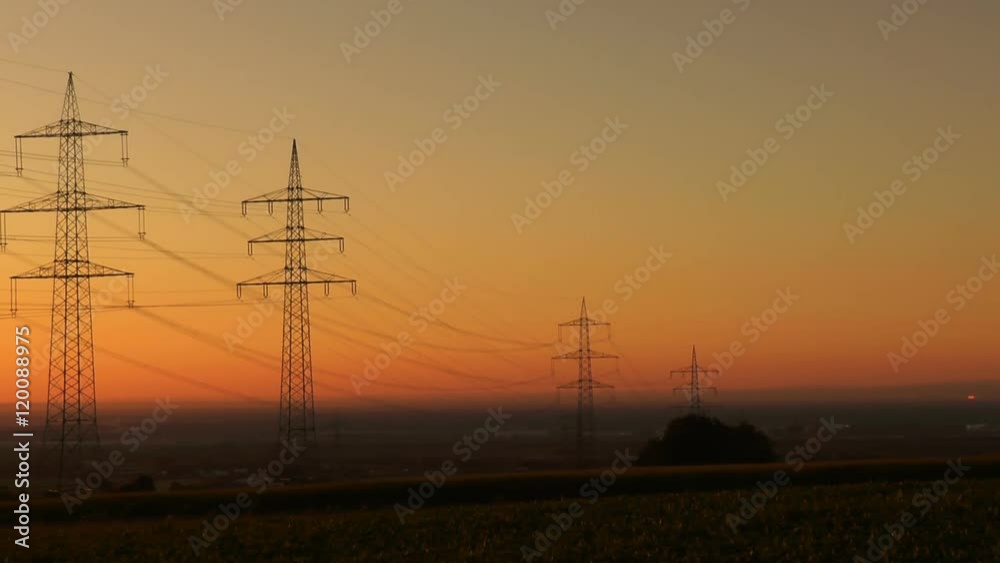 Silhouettes of electricity pylons at dawn