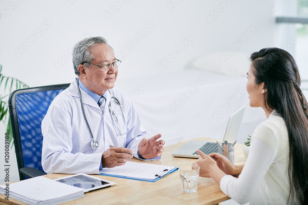 Vietnamese doctor consulting female patient in his office Vietnamese doctor consulting female patient in his office