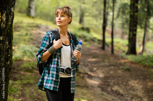 woman traveler with backpack and a bottle of water in a forest photo