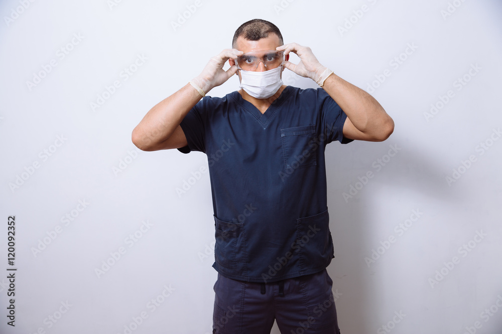 Fototapeta premium Portrait of young doctor with mask on a white background. Concept surgery and healthy