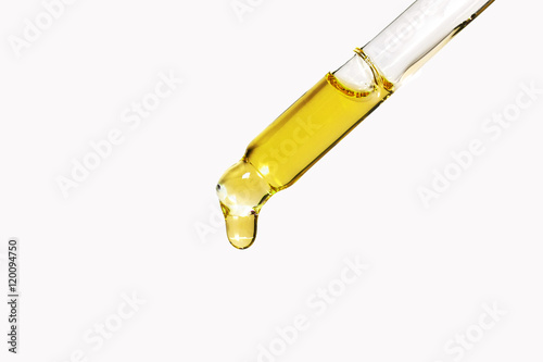 transparent glass pipette with a Golden liquid dripping photo