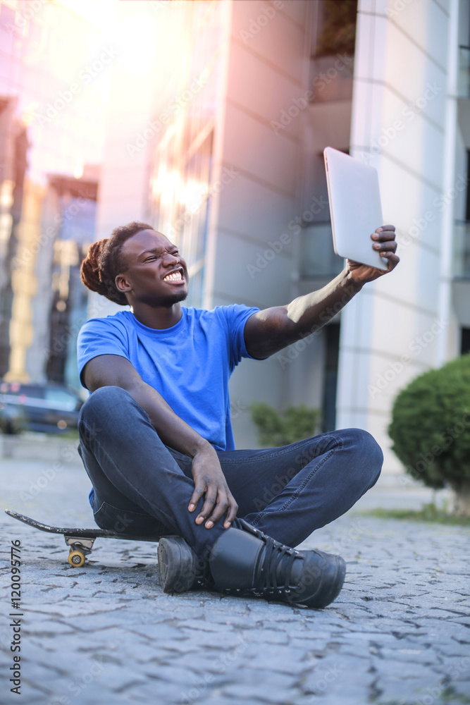 Obraz premium Sitting guy doing a selfie with a tablet