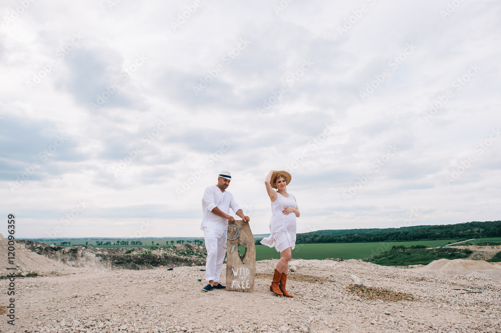 Pregnant woman and man sitting on rock Pregnant woman and man sitting on rock