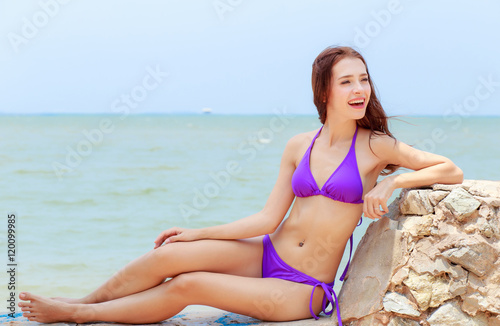 Beautiful women, bikinis behind purple sea sunny afternoon.