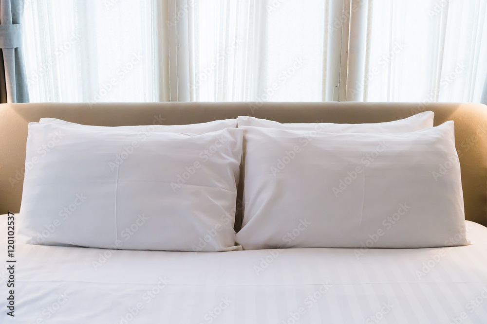 several white pillows on a white bed