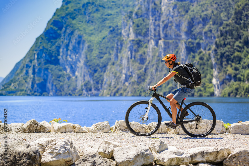 Fototapeta premium Cycling woman at the lake Shore of Garda lake in Italy