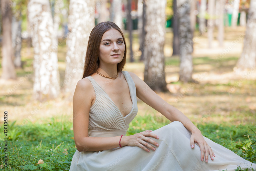 Fototapeta premium Beautiful girl in dress sitting on the grass