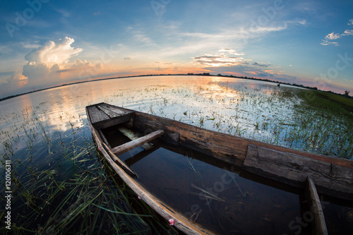 Sunset on the river with a wooden boat moored.