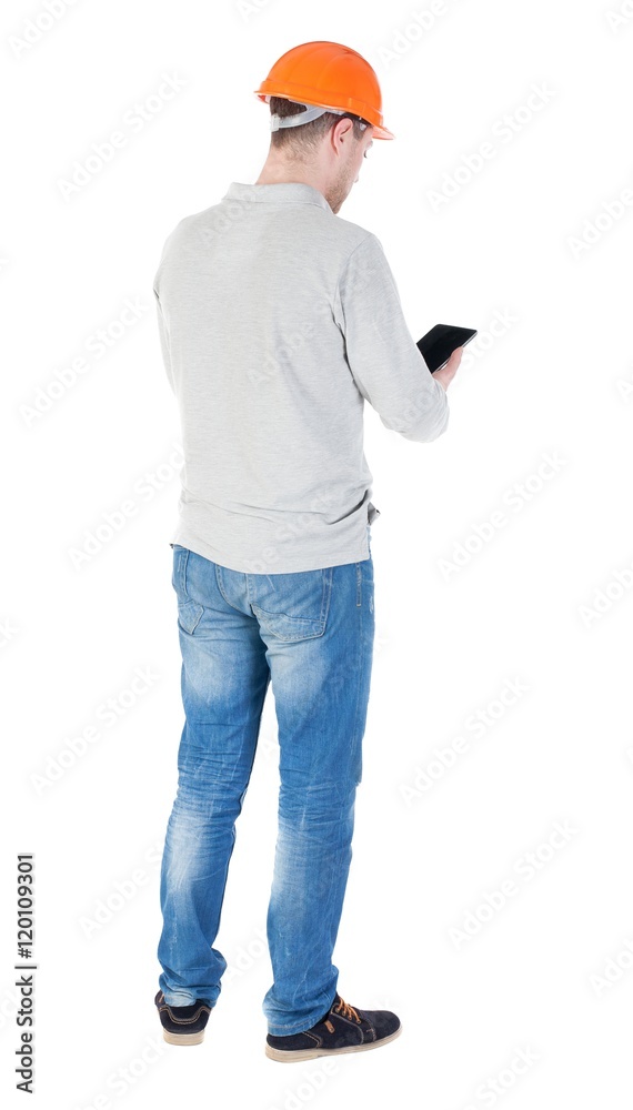 young engineer in a protective helmet with tablet computer in the hands of. Rear view people collection. backside view of person. Isolated over white background. engineer is reporting in the tablet young engineer in a protective helmet with tablet computer in the hands of. Rear view people collection. backside view of person. Isolated over white background. engineer is reporting in the tablet