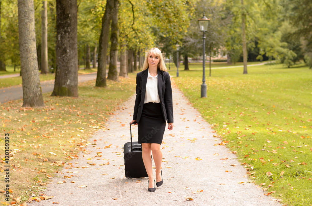 Fototapeta premium Elegant professional woman pulling her luggage