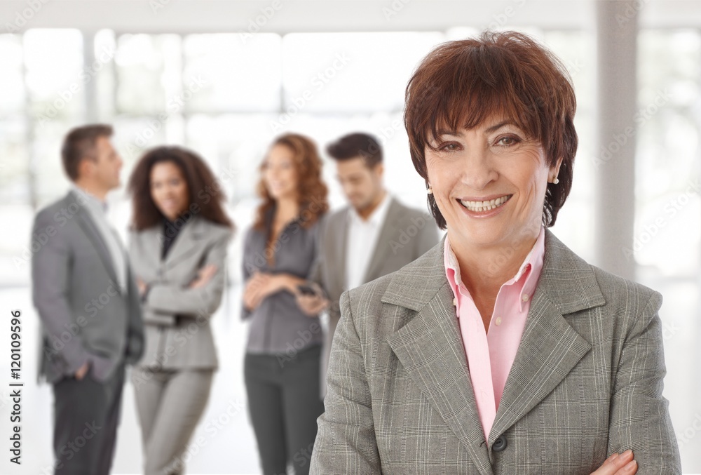 Middle-aged businesswoman in front of colleagues Middle-aged businesswoman in front of colleagues