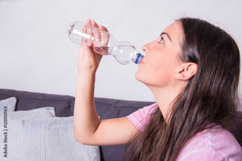 Portrait of a young beautiful woman drinking water out of the bo Portrait of a young beautiful woman drinking water out of the bo