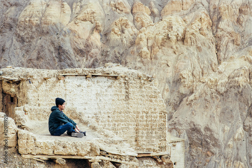 Young male traveler sitting on the sand cliff thinking about or looking forward to something in Leh LadakhIndia photo