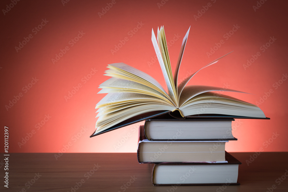 Fototapeta premium Libro aperto su pila di libri chiusi