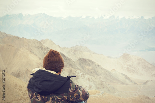 Young male traveler sitting on the sand cliff thinking about or looking forward to something in Leh LadakhIndia photo