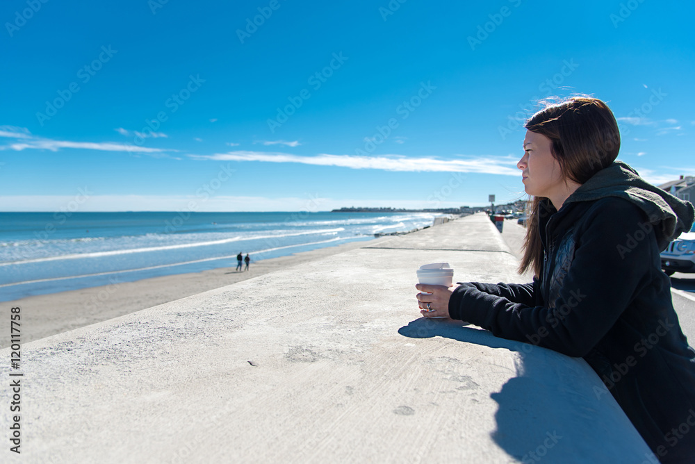 Single woman on beach drinking coffee