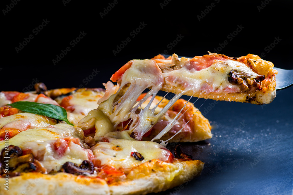 cut off a slice of pizza. melted cheese stretches from the piece cut off a slice of pizza. melted cheese stretches from the piece